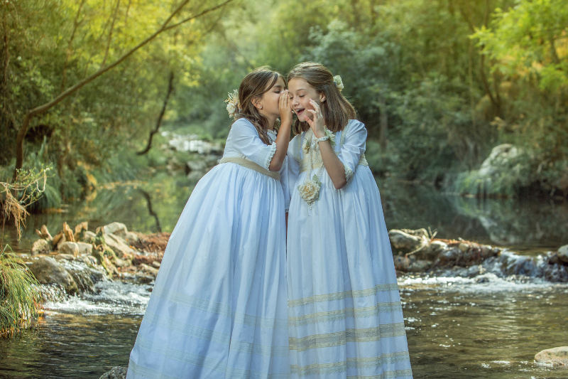 Dos niñas vestidas de Comunión contándose secretos al oído